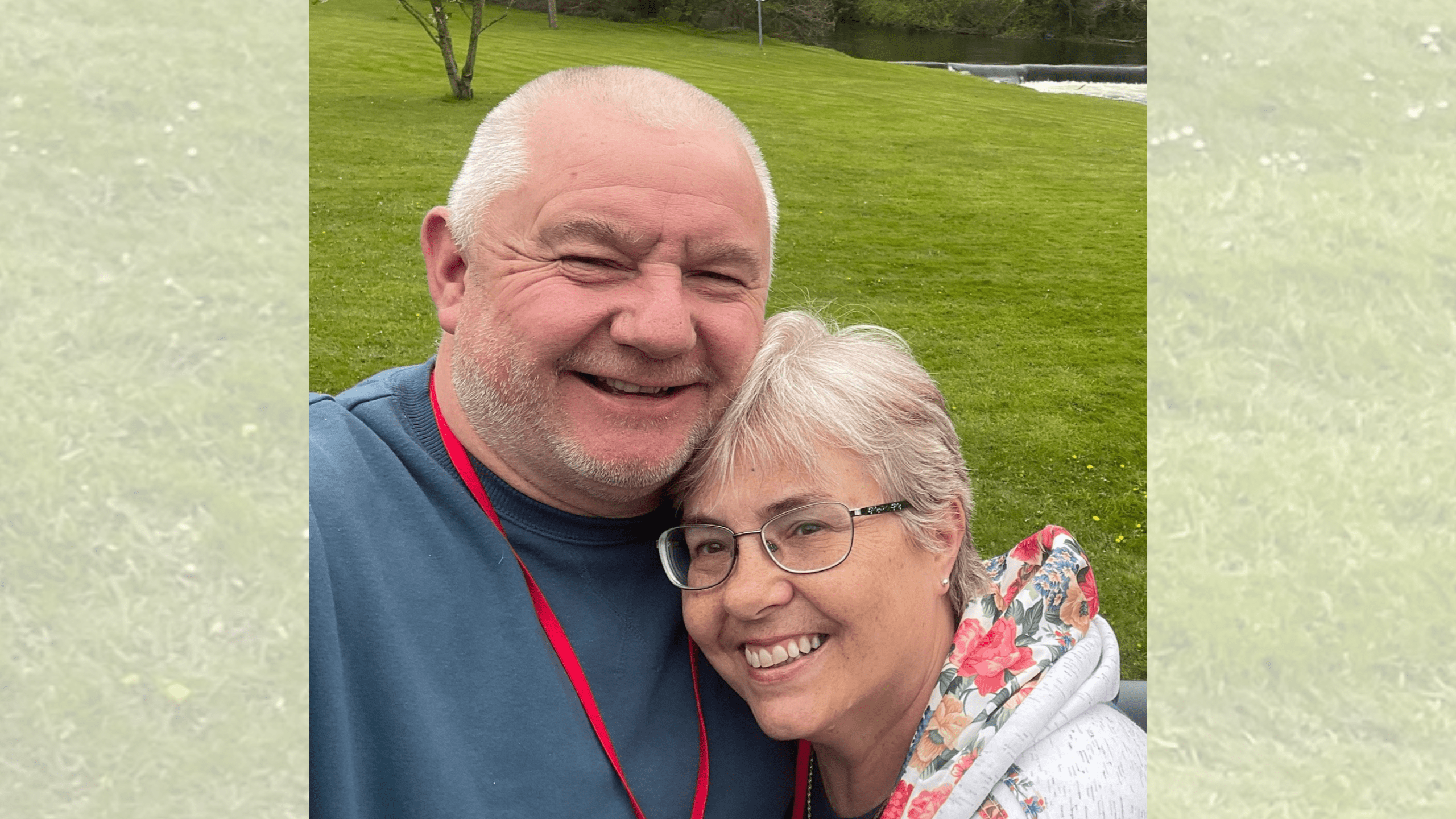 A middle-aged man and woman smiling together for a selfie outdoors.