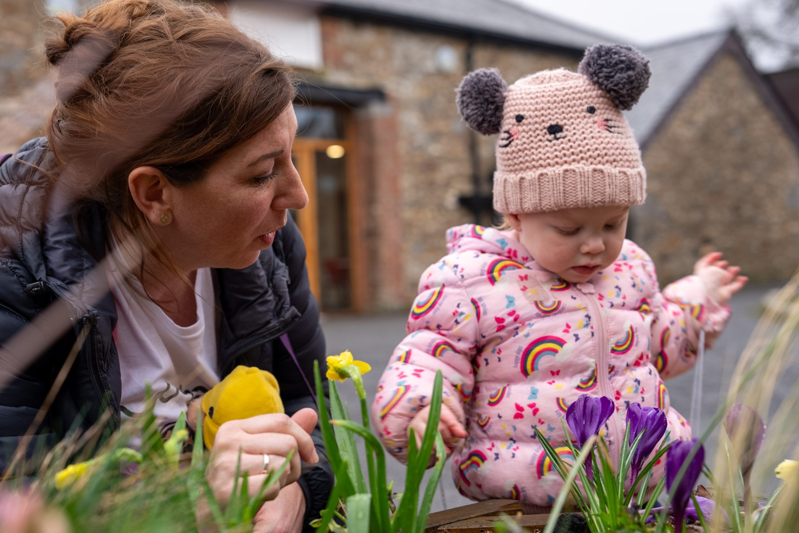 Mother and infant girl look at flowers at Harcombe House in Devon