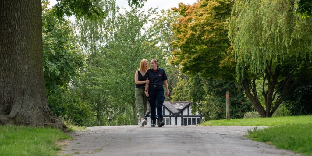 two women, a firefighter in uniform and her partner walking through the park